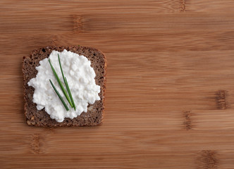 Fototapeta na wymiar Sliced rye bread with cottage cheese on wooden table.