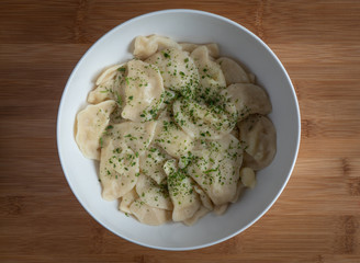 Dumplings filled with mashed potato in bowl on wooden table