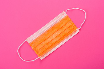 Medical mask on a colored background, a means of protection against coronovirus and epidemic