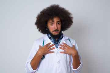 Shocked scared African American doctor man keeps hands on chest, mouth widely opened, stares at camera realizes that she forgot to pay bills isolated indoors. Girl saying: Who, me?