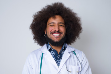 Fototapeta na wymiar Cute young doctor male with afro hairstyle wearing medical uniform blinking her eyes with pleasure having happy expression. Facial expressions and people emotions concept.