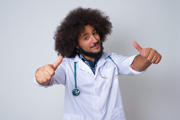 African American doctor man over isolated background approving doing positive gesture with hand, thumbs up smiling and happy for success. Looking at the camera, winner gesture.