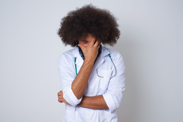Indoor portrait of beautiful doctor man, wearing medical uniform, making facepalm gesture while...