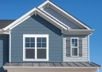 Elegant blue horizontal vinyl siding, shingle and vertical siding in a double gable roof with white...
