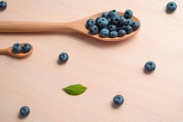 Fresh blueberries lie in a wooden spoon on a natural wooden background. Eco products for human health. Healthy eating concept flat lay. Copy spase