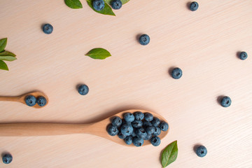 Fresh blueberries lie in a wooden spoon on a natural wooden background. Eco products for human health. Healthy eating concept flat lay. Copy spase