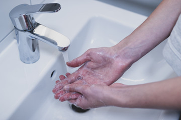 Woman washing her hands with soap in the sink