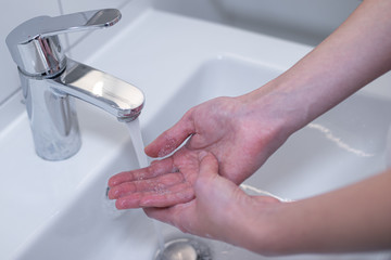 Woman thoroughly washing her hands with soap in the sink