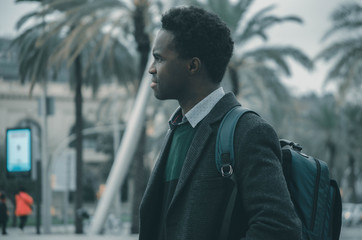 A young black student with a bag in his shoulder