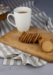 White cup with place for text. Breakfast is on the table. Cup with coffee and round homemade cookies. Mug with a drink and a snack. Mockup for designs. 