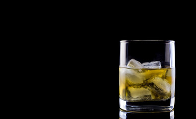 Tumbler glass with whiskey on black background