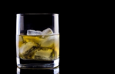 Tumbler glass with whiskey on black background