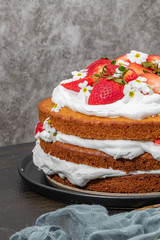 Strawberry cake, strawberry sponge cake with fresh strawberries and sour cream on a dark background