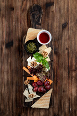 Wine platter with assorted snacks such as grissini, cheese, sliced meat and nuts on wooden board