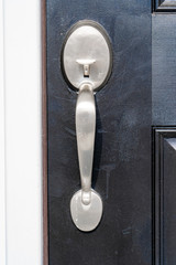 Close-up view of brand new nickel single cylinder front door handle set on a black wooden door