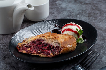 Cherry strudel with cinnamon and scoop of vanilla ice cream, served with a pot of tea