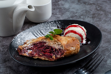 Cherry strudel with cinnamon and scoop of vanilla ice cream, served with a pot of tea