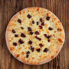 Hot focaccia with sun-dried tomatoes and mozzarella on wooden table in italian restaurant
