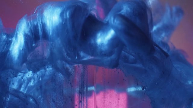 Paint splash. Surreal power. Faded denim blue glitter fluid cloud over pink pyramid in water.
