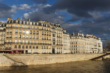 Fototapeta na wymiar The traditional French house with typical balconies and windows located on parisian quay . Paris.