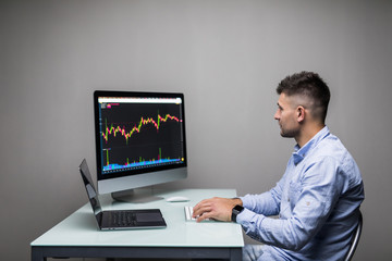 Young man sitting on work market view of the computer screens of a stock broker trading in a bull market showing ascending graphs