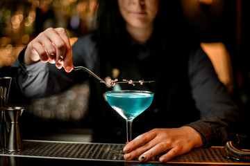 brunette woman bartender carefully decorates glass with cocktail.