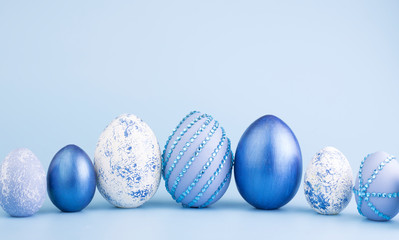 Chicken eggs painted in blue on a blue background. Creative card with Easter. Copy space