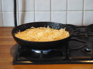 Cabbage is fried in a black cast iron pan on the kitchen stove.Natural home-made food.