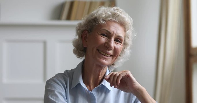 Pleasant happy healthy older mature woman looking at camera. Head shot close up smiling cheerful middle aged single granny posing for photo. Old senior retired lady showing positive emotions.