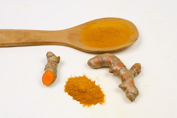 Turmeric powder in a wooden spoon and fresh turmeric roots isolated on a white background is an ingredient in turmeric foods and ingredients in skin care products. Turmeric helps strengthen the skin.
