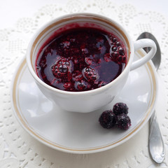 Cup on a saucel with kisel made of black currant berries