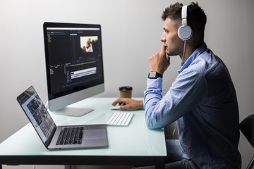 Confident man video editor works with footage in creative office studio.
