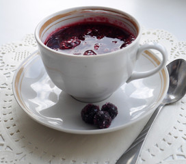 Cup on a saucel with kisel made of black currant berries
