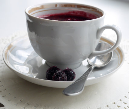 Cup on a saucel with kisel made of black currant berries