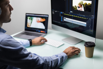Young man video editor with works with footage on his personal computer with big display in modern office