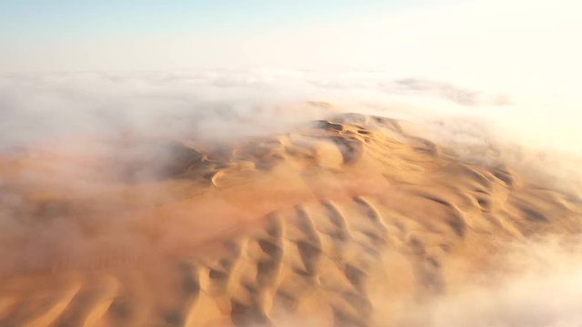 Aerial time lapse of fog flowing over massive sand dunes in the Empty Quarter. Liwa desert, Abu Dhabi, United Arab Emirates.