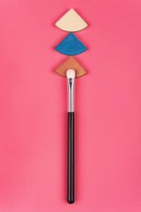 Cosmetic palette and face shadow with brushes lies on a pink background