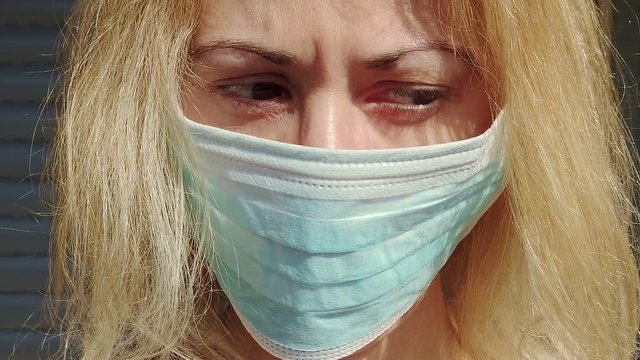 SLOW MOTION: front close-up of a blonde girl with a sanitary mask. Concept of the epidemic outbreak, quarantine for public health care and outbreak of the corona-virus.