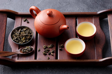 Green tea oolong in teapot and chawan bowls, cups on a wooden tray. Grey background. Close up. - obrazy, fototapety, plakaty
