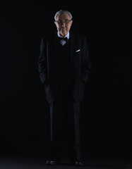Fototapeta premium old man in a black suit on a black studio background