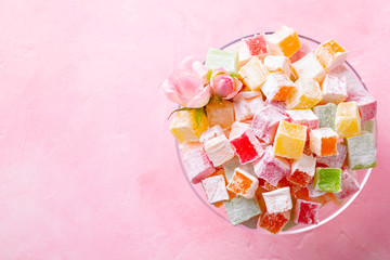 Assorted Turkish delights on glass cake stand. Pink background. Copy space. Top view.