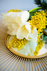 Obraz na płótnie Canvas Bouquet of white tulips and mimosa flowers on mirror tray