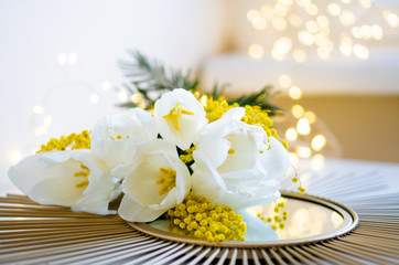 Fototapeta na wymiar Bouquet of white tulips and mimosa flowers on mirror tray