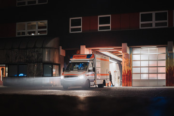 Fire station at night with fire trucks responding to emergency call and leaving