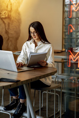 Attractive woman sitting at table and working on laptop