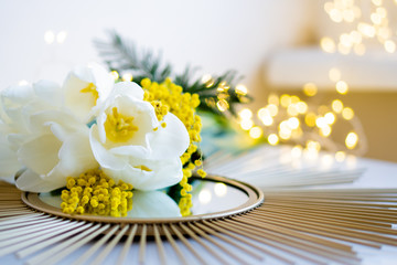 Bouquet of white tulips and mimosa flowers on mirror tray