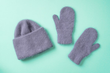 Christmas and New Year cozy holiday composition. Knitted mittens ond hat on blue background. Flat lay, top view