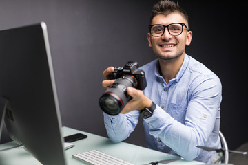 Young photographer busy retouching his images on his computer with his camera work from his home studio