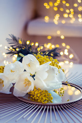 Bouquet of white tulips and mimosa flowers on mirror tray