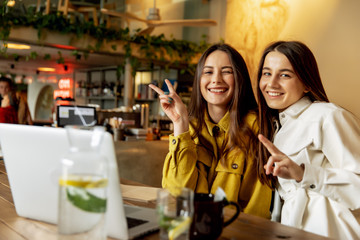 Cheerful young ladies hugging each other at local cafe